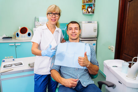 My smile is perfect. My dentist is the best. Portrait of a dentist and patient in a pleasant environment. The office has specialized equipment for the treatment of all types of dental diseases.の写真素材