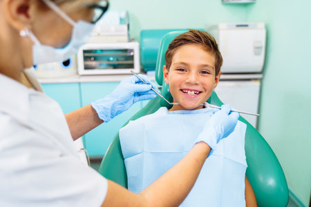 Small, young patient boy is happy with a visit to the dentist. Concept of painless dental treatment. Beautiful, wide smile of a child sitting in a dental chair in a doctor's office.の写真素材