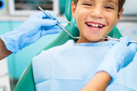 Small, young patient boy is happy with a visit to the dentist. Concept of painless dental treatment. Beautiful, wide smile of a child sitting in a dental chair in a doctor's office.の写真素材