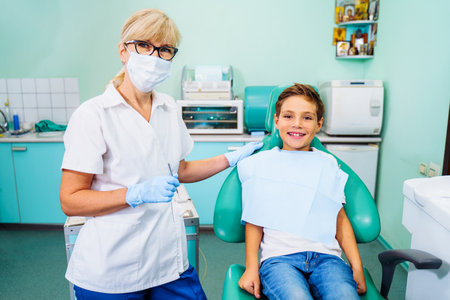 A cute baby is being examined by a professional pediatric dentist. Very happy boy after the visiting of doctor at the clinic with beautiful white smiles. Copy space.の写真素材