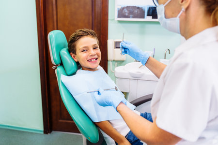 Dental inspection is being given to Beautiful man surrounded by dentist and his assistant. Woman dentist in the dental office talking to the patient and getting ready for treatment.の写真素材