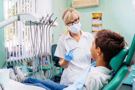 Dental inspection is being given to Beautiful man surrounded by dentist and his assistant. Woman dentist in the dental office talking to the patient and getting ready for treatment.の写真素材