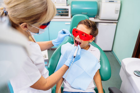 Protection of vision, eyesight against bright light and radiation from dental device with red or orange specialized glasses. Patient comfort comes first. Appointment at professional dentist in clinic.の写真素材
