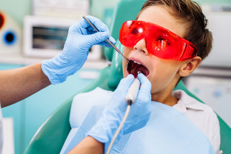 Patient with open mouth in dental clinic. Preparation for dental treatment. Using cotton wool to collect saliva, bor machine, dental mirror, tweezers and other devices. Timely treatment is important.の写真素材