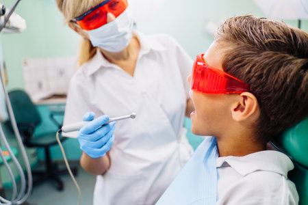 Dental inspection is being given to Beautiful man surrounded by dentist and his assistant. Woman dentist in the dental office talking to the patient and getting ready for treatment.の写真素材