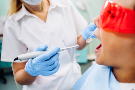 Dental inspection is being given to Beautiful man surrounded by dentist and his assistant. Woman dentist in the dental office talking to the patient and getting ready for treatment.の写真素材