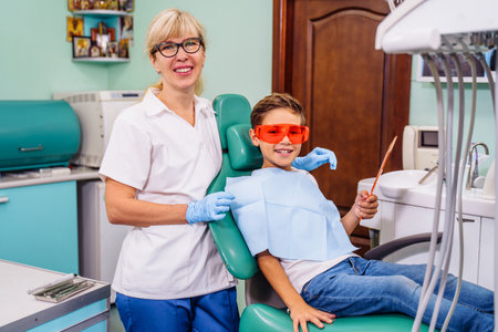 A cute baby is being examined by a professional pediatric dentist. Very happy boy after the visiting of doctor at the clinic with beautiful white smiles. Copy space.の写真素材