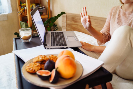 Attractive, blonde Caucasian ethnicity emotionally communicates via video, using tablet or computer. Adds gestures to speech. Looking at screen in front of her and showing ok sign. Close shot.の写真素材