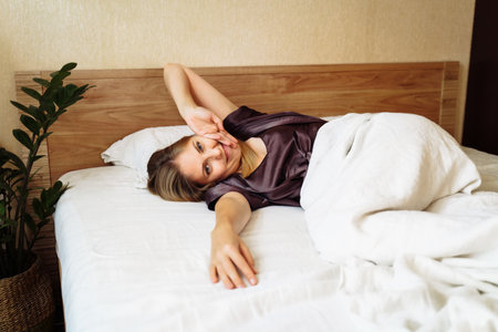 A beautiful blonde stretching sweetly in her bed on an early sunny summer morning. Lazy weekend. The freelancer himself creates the schedule of his day. Top view. Lying in the bed.の写真素材