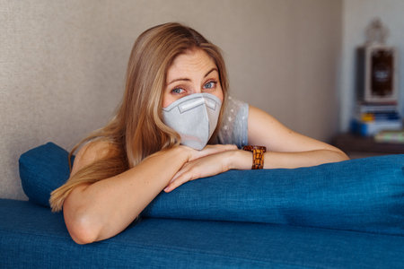 Sad European girl worried about serious   infection that swept the world. Lying on couch, dreaming of everything will work out, of traveling and the ordinary course of life.の写真素材