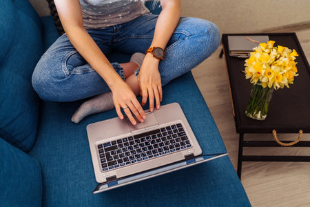 Attractive blonde girl wearing a protective mask works hard and responsibly with a laptop remotely at home. Isolated due to the world  epidemic during the quarantine periodの写真素材