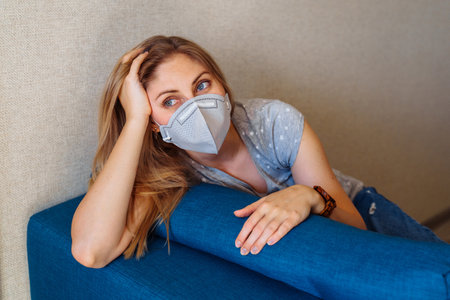 Sad European girl worried about serious infection that swept the world. Lying on couch, dreaming of everything will work out, of traveling and the ordinary course of life.の写真素材