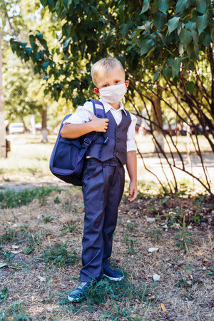 new rules for staying at school. An elementary school student goes to school in the morning. Always wear a protective medical mask. Looks smart and neat in a new uniform.の写真素材