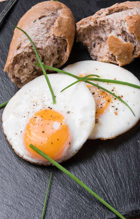 Roeasted Round Eggs with Fresh Bread on Black Stone Board
