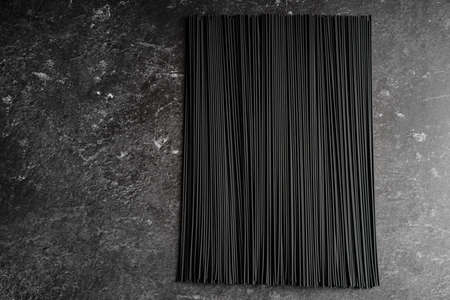 Black dry raw noodles spaghetti on dark backgroundの写真素材
