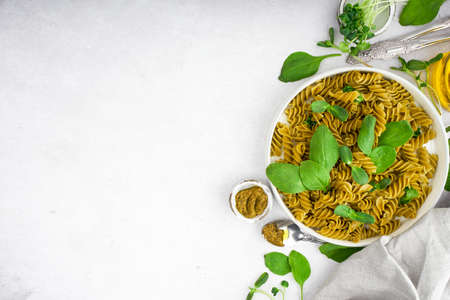Green spinach pasta with microgreen and pesto in a white bowl with silver cutlery. Gourmet italian meal. Top view. Flatlay. Concept health eatingの写真素材