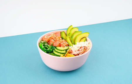An overhead photo of poke bowl, traditional Hawaiian and Japanise raw fish salad, from seaweed,...