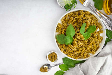 Green spinach pasta with microgreen and pesto in a white bowl with silver cutlery. Gourmet italian meal. Top view. Flatlay. Concept health eatingの写真素材