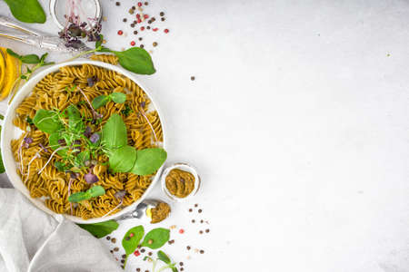 Green spinach pasta with microgreen and pesto in a white bowl with silver cutlery. Gourmet italian meal. Top view. Flatlay. Copy spase. Concept health eatingの写真素材