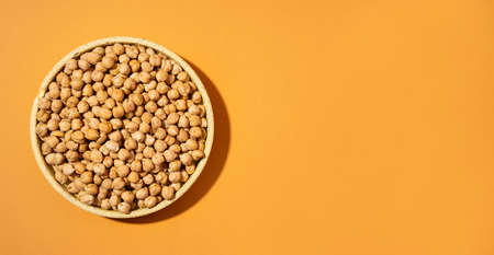 Chickpeas in small yellow ceramic plate bowl isolated on beige orange background.vegetarian dish. style minimalism banner. on bowl close up - concept healthy vegan diet protein organic food dishの写真素材