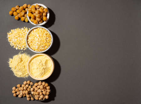 Raw and cooked chickpeas, chickpea flour and flakes in small ceramic plates, banner copyspace black background. Vegetarian dish. style minimalism. healthy vegetarian food concept, protein foodの写真素材