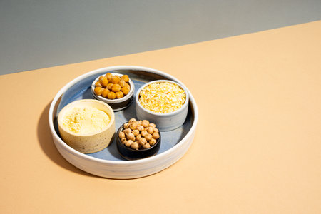 Raw and cooked chickpeas, chickpea flour and flakes in small ceramic plates, isometric projection diagonal beige and blue background. Vegetarian dish. style minimalism. healthy vegetarian food concept, protein brain foodの写真素材