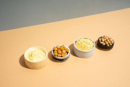 Raw and cooked chickpeas, chickpea flour and flakes in small ceramic plates, isometric projection diagonal beige and blue background. Vegetarian dish. style minimalism. healthy vegetarian food concept, protein brain foodの写真素材
