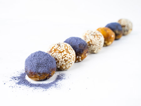 Homemade blue matcha energy balls in a ceramic bowl plate on a bright marble background top view, healthy sweets made of nuts and date, dried apricots, sesame, cashew nuts. Concept vegeterian diet sweet brain food. Copy spaceの写真素材