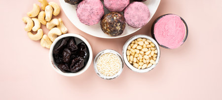 Homemade pink matcha energy balls in a ceramic plate on a minimalistic pink background top view, healthy sweets made of nuts and date, dried apricots, prunes, sesame, cashew nuts, Pine nuts. Concept vegeterian diet sweet brain food. Copy spaceの写真素材