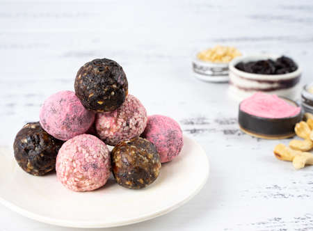 Homemade pink matcha dragon fruit energy balls, top view, healthy sweets made of nuts and date, prunes, sesame, cashew nuts, Pine nuts. Concept vegeterian diet candy brain food. Copy spaceの写真素材