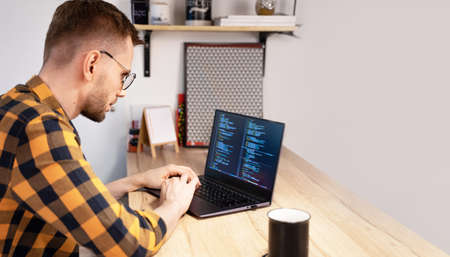 Male programmer using Programs computer code in a bright Home. Concept programmer Day.