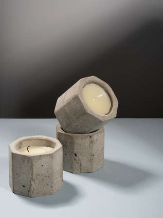 Creative diagonal isometric projection. Composition with scented candles of soy wax in a concrete candlestick on a blue and white background. Minimalism. Shadow. Natural materialの写真素材