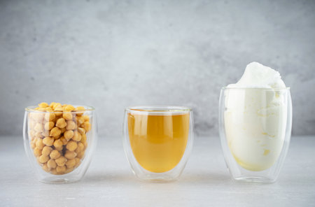 Chickpea aquafaba. Egg replacement. Vegan cooking concept. Chickpea, chickpea water, whipped chickpeas liquid, called aquafaba, in glass cup. On a gray background. Sustainable. Natural productsの写真素材