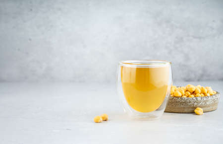 Chickpea aquafaba. Egg replacement. Vegan cooking concept. Chickpea water in glass cup and chickpea in a ceramic handmade plate. On a gray background. Natural eco-friendly products. Copy spaceの写真素材