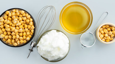 Chickpea aquafaba. Egg replacement. Vegan cooking concept. whipped chickpeas liquid in glass bowl. chickpea in a ceramic plate. whisk. gray isolated background. Top view. Copy space. Banner. Mock upの写真素材