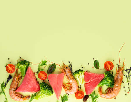 Shrimp, tuna, broccoli, cherry tomatoes and spinach on a bright green background. Concept Healthy Pescataian diet. Seafood, fish, vegetables.Pescetarian and Flexsitarian diet plan products.Copy spaceの写真素材