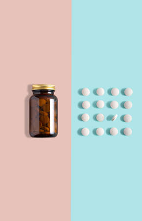 Vitamin capsules. pill in glass bottle on pink and blue background.trendy shadows. Concept wellness and heathy lifestyle. Modern minimalistic photo. Dual color. Copy spaceの写真素材