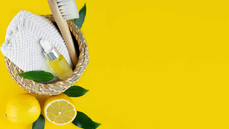 Fresh lemon, Small bottle with lemon essential oil in bamboo basket and towel on a yellow background. Cosmetic essence. Organic natural product for Aromatherapy and skin care. Horisontal. Copy spaceの写真素材
