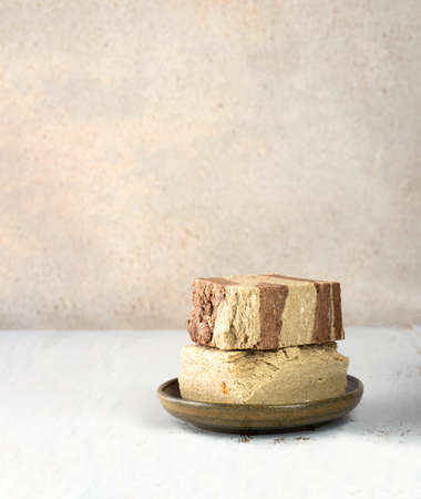 Minimalistic. Tasty eastern sweet dessert halva from sunflower seeds, cocoa and tahini on beige wooden background.Traditional dessert confection in Middle East, Balkans and west Asia.Verticalの写真素材