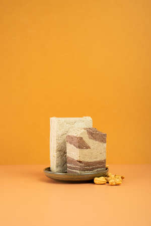 Modern still life. Tasty eastern sweet dessert halva from sunflower seeds, cocoa and tahini on dual...