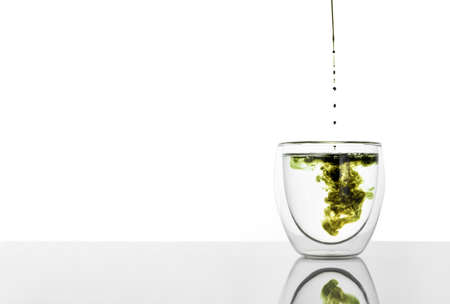 Mixing water and liquid chlorophyll with dropper. Fresh herbs and green towel on a table. Concept of...