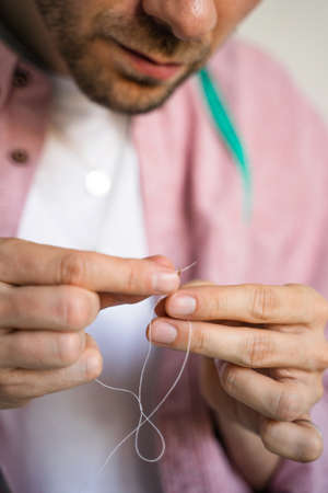 Sewing clothes for pets. Tailoring clothes for cats. A laughing tailor in white t-shirt is sewing...