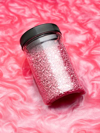 Package of purple shiny crystal salt on a bathroom beige towel. Jar of shimmering purple sea salt...