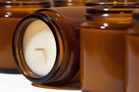 Aroma Soy and coconut wax candles in brown glass jars. Scented calming candle. Natural essential candles in a Amber jar. Aromatherapy, wellness and relax in spa product. close up. macro.の写真素材