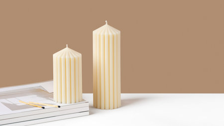 Handmade olive wax pillar candle on a neutral beige and white background. Sustainability vegan candle, natural materials. Minimalistic, cozy atmosphere modern photo. copyspace. horizontal bannerの写真素材