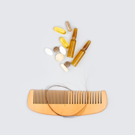 Cosmetic ampoules with serum and vitamins for hair growth, beauty hair restoration. Wooden comb with...