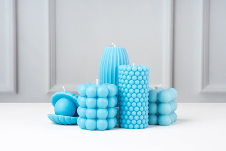 Handmade olive wax different forms blue color candle on a on the white table at home. Sustainability vegan candle, natural materials. Minimalist, modern photo. copyspace. Horizontal.の写真素材