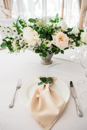 wedding table decorated by plates, knives and forks, candle, moss, flowers roseの写真素材