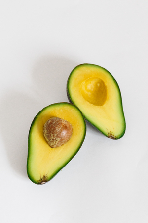 Whole and cut in half of avocado isolated on white background. Simple and delicious tasty recipes for everything from breakfast to dessert. Every meal of the day. For diet helps improve your overall.の写真素材
