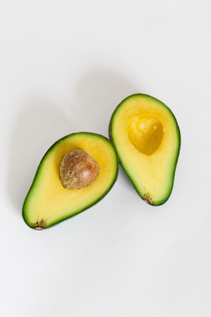 Whole and cut in half of avocado isolated on white background. Simple and delicious tasty recipes for everything from breakfast to dessert. Every meal of the day. For diet helps improve your overall.の写真素材